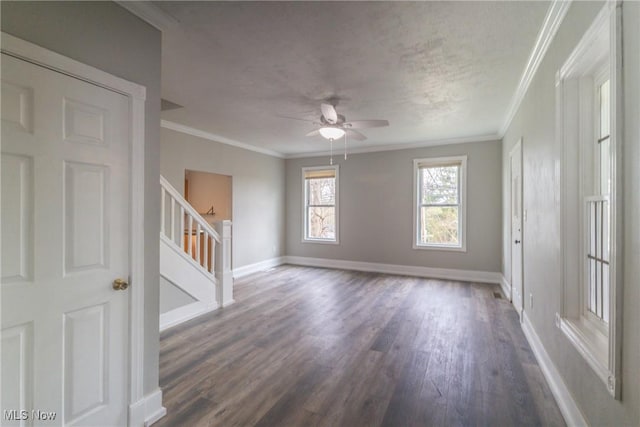 spare room featuring ornamental molding, baseboards, a ceiling fan, and stairs