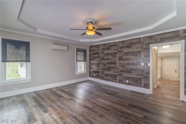 empty room featuring a tray ceiling, ceiling fan, baseboards, and an AC wall unit