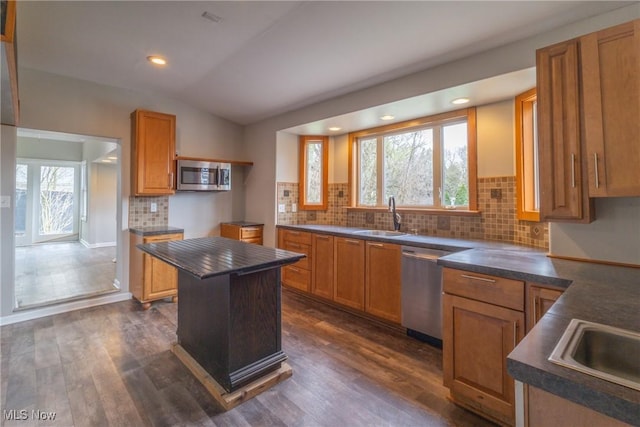 kitchen featuring appliances with stainless steel finishes, a sink, and dark countertops