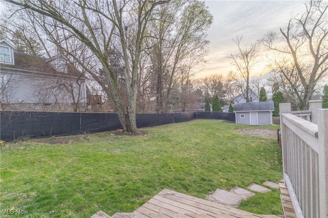 yard at dusk with a fenced backyard, a storage unit, and an outdoor structure