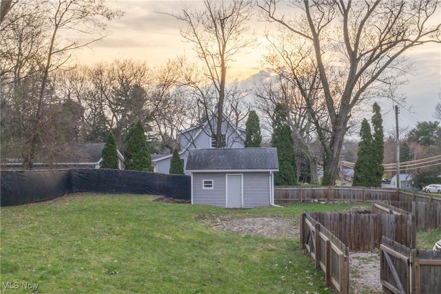 view of yard featuring a storage shed, a fenced backyard, and an outdoor structure