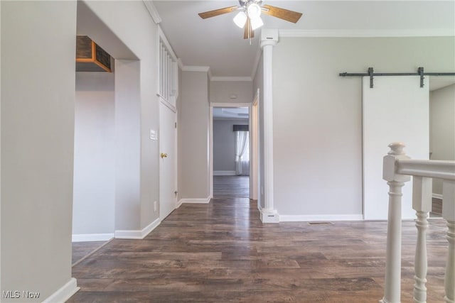 corridor featuring visible vents, baseboards, a barn door, ornamental molding, and wood finished floors