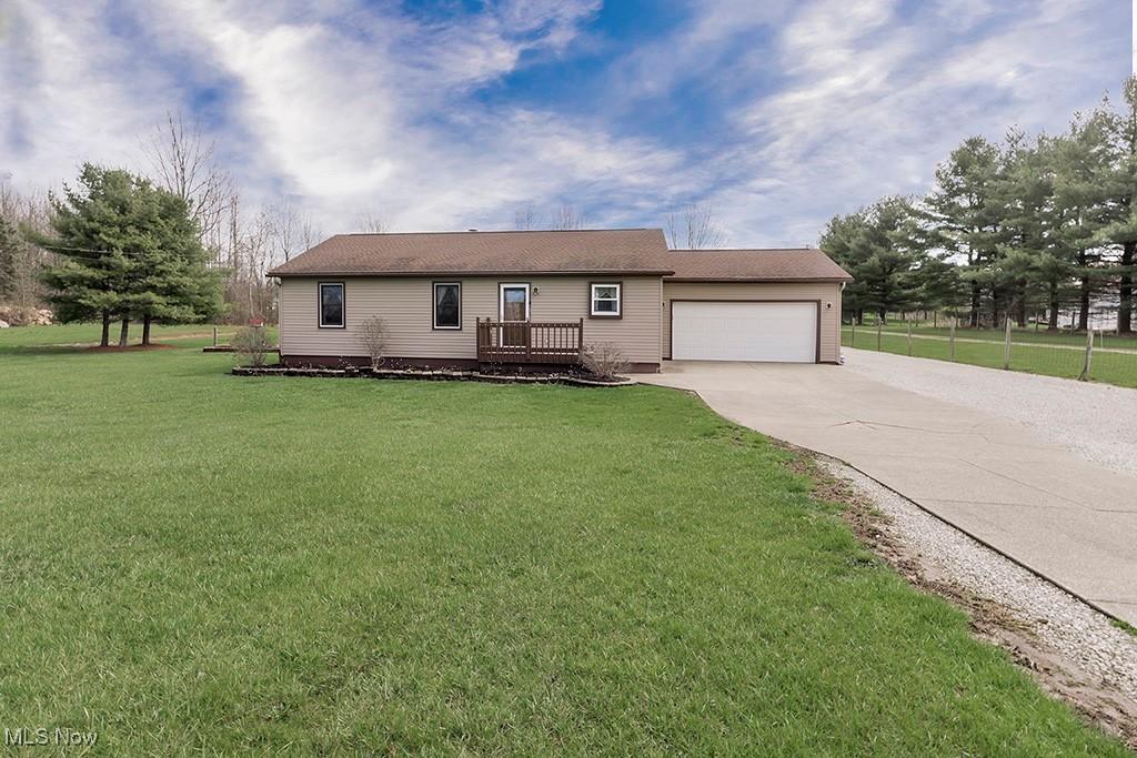 single story home with a garage, driveway, and a front lawn