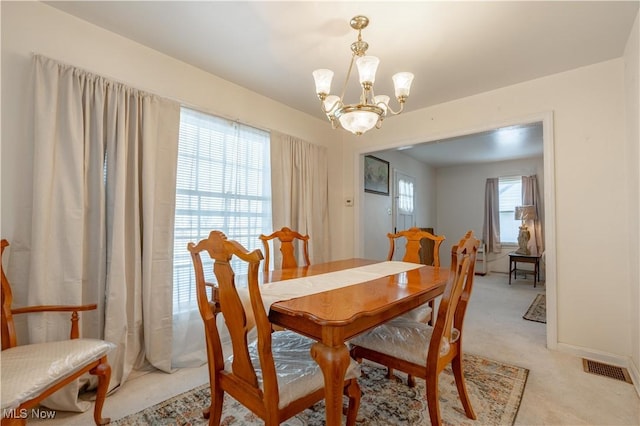 dining space featuring light colored carpet, a chandelier, and visible vents