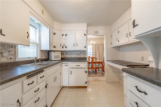 kitchen with a sink, dark countertops, and tasteful backsplash