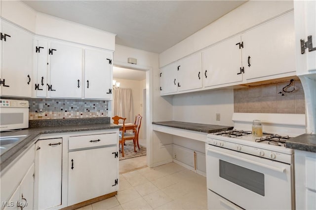 kitchen featuring dark countertops, white cabinets, backsplash, and gas range gas stove