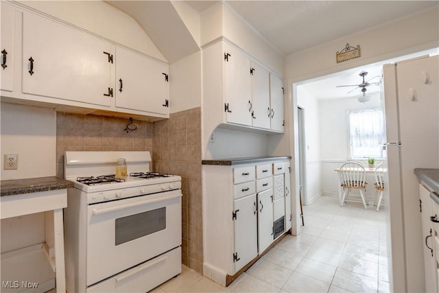 kitchen featuring light tile patterned floors, dark countertops, white appliances, and white cabinetry