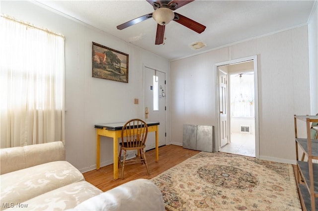living room with crown molding, visible vents, a healthy amount of sunlight, and wood finished floors