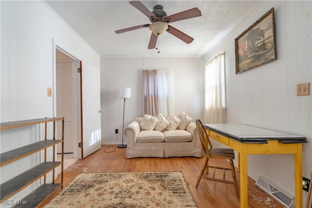 living room with visible vents, ornamental molding, a ceiling fan, and wood finished floors