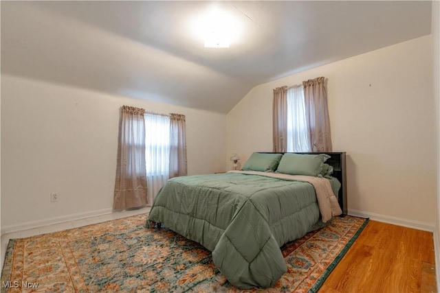 bedroom featuring baseboards, vaulted ceiling, and wood finished floors