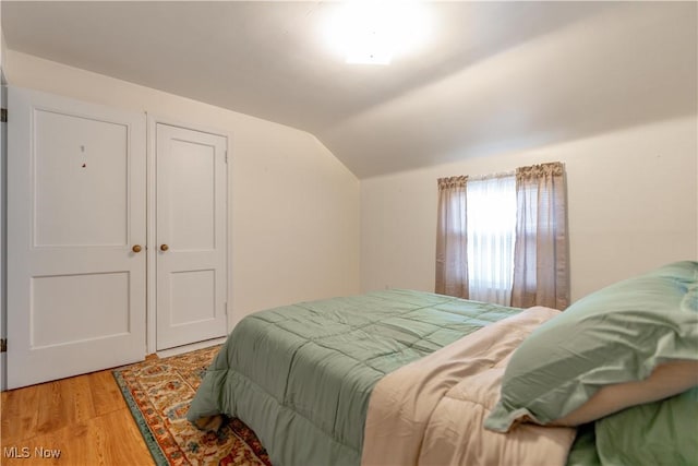 bedroom with wood finished floors and vaulted ceiling