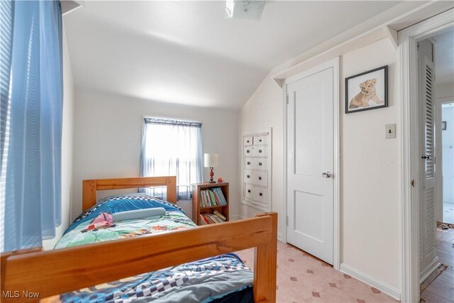 bedroom featuring baseboards, lofted ceiling, and light floors