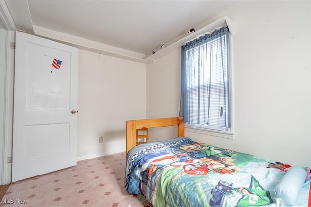 bedroom featuring baseboards, light floors, and multiple windows