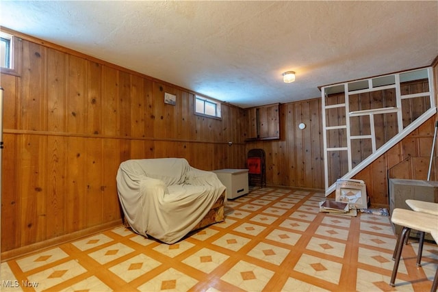 living area with wooden walls, a textured ceiling, tile patterned floors, and baseboards