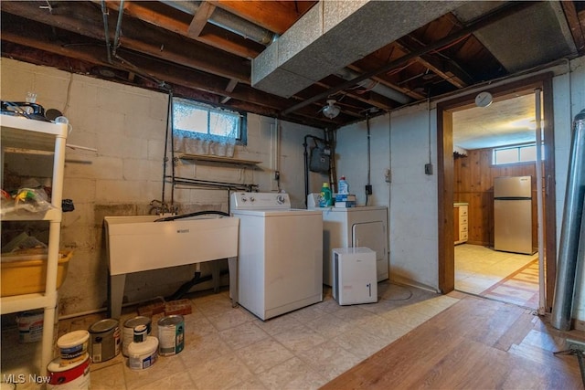clothes washing area featuring laundry area, a sink, plenty of natural light, and separate washer and dryer