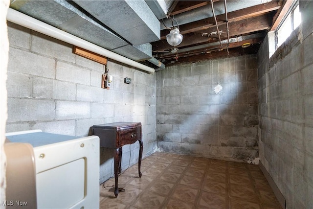 unfinished below grade area featuring concrete block wall and washer / clothes dryer