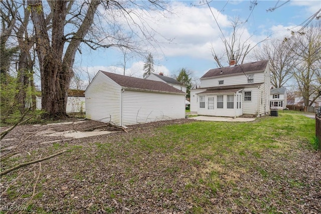 back of property with an outdoor structure, a chimney, and a yard