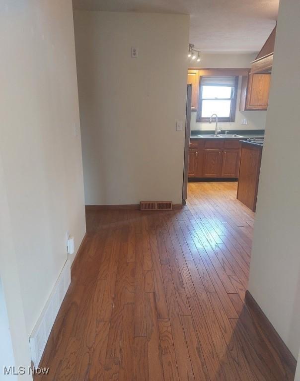 kitchen featuring brown cabinets, light wood finished floors, a sink, and visible vents