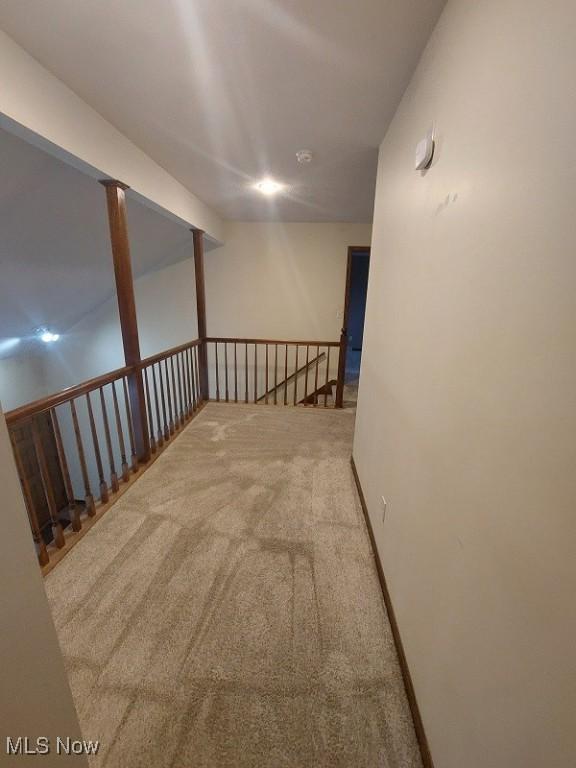 corridor with baseboards, an upstairs landing, and carpet floors