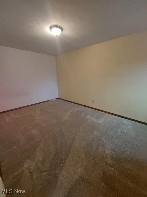 spare room featuring baseboards and carpet floors