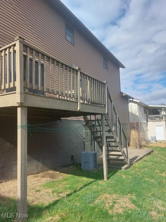 rear view of house with central air condition unit, a wooden deck, stairs, and a lawn
