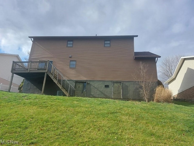 rear view of house with stairs, a deck, and a lawn