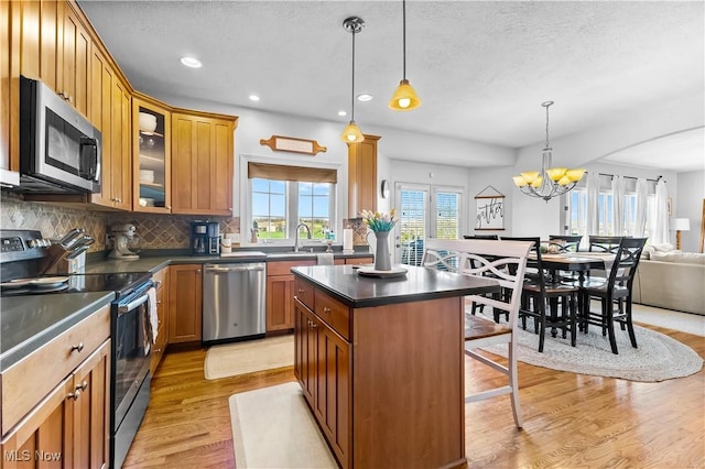 218 Canterbury Ct, Columbiana, OH 44408 - kitchen with light wood-type flooring, backsplash, dark countertops, a kitchen bar, and appliances with stainless steel finishes
