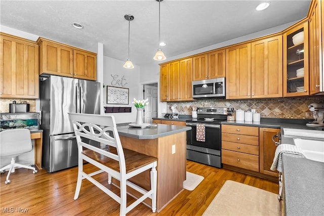 218 Canterbury Ct, Columbiana, OH 44408 - kitchen featuring wood finished floors, glass insert cabinets, a breakfast bar area, and appliances with stainless steel finishes