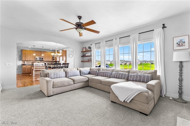 218 Canterbury Ct, Columbiana, OH 44408 - living area with arched walkways, light colored carpet, ceiling fan with notable chandelier, and baseboards