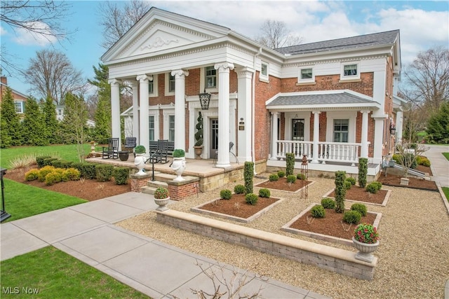 128 Center St, Milan, OH 44846 - greek revival house featuring a porch, a shingled roof, and brick siding