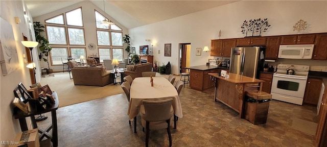 kitchen with white appliances, open floor plan, a kitchen island, dark countertops, and high vaulted ceiling
