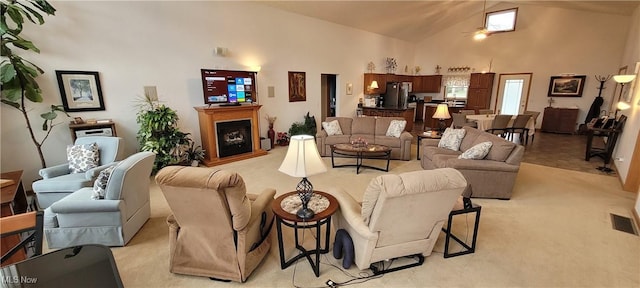 living area with light carpet, a fireplace, high vaulted ceiling, and visible vents
