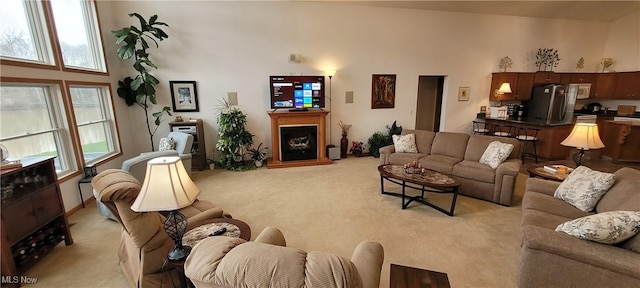living area with light carpet and a fireplace with raised hearth