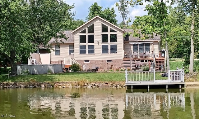 back of house featuring roof with shingles, a lawn, a deck with water view, and stairway