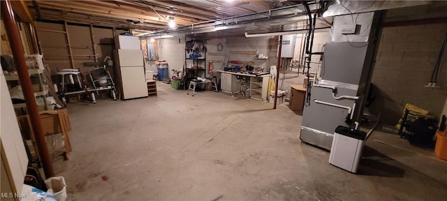 unfinished basement featuring freestanding refrigerator and heating unit