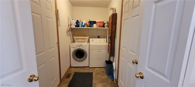 clothes washing area featuring washer and dryer, visible vents, laundry area, and a textured ceiling