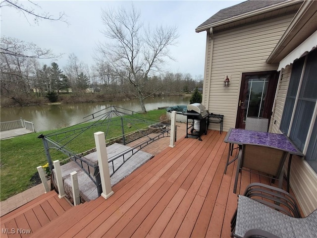 wooden terrace featuring a water view, grilling area, and a lawn