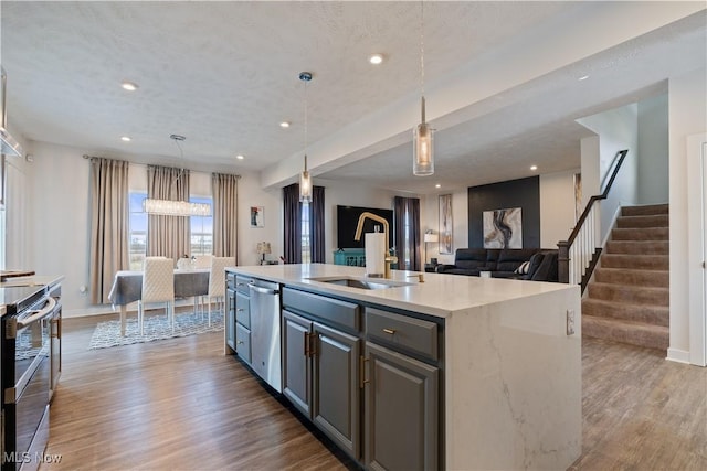 5454 Schueller Blvd, Sheffield Village, OH 44054 - kitchen featuring wood finished floors, a kitchen island with sink, a sink, hanging light fixtures, and stainless steel appliances