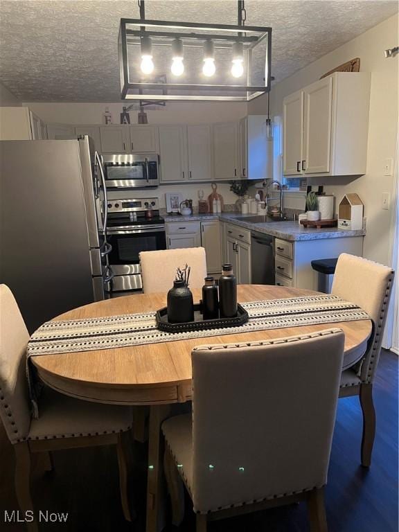 kitchen featuring decorative light fixtures, a sink, light countertops, appliances with stainless steel finishes, and a textured ceiling