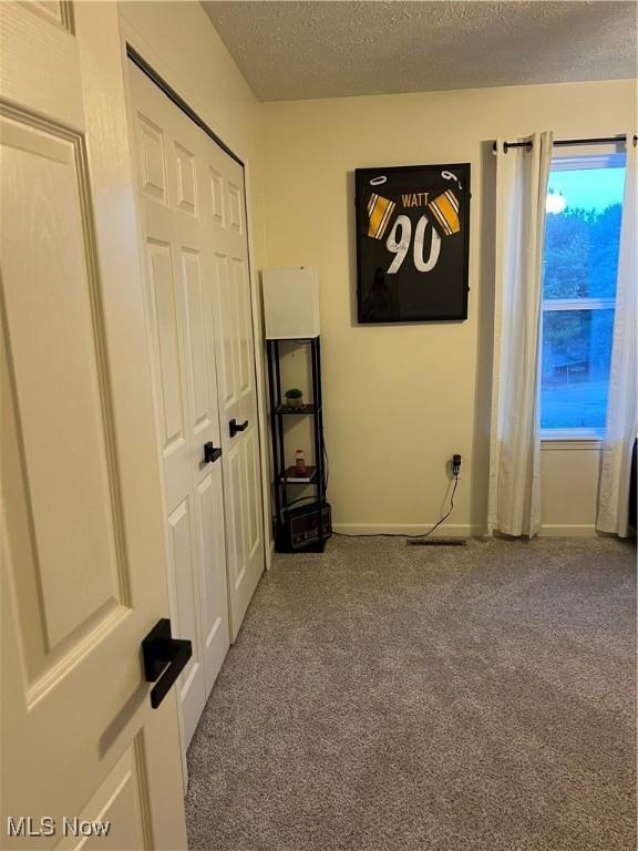 unfurnished bedroom with a closet, a textured ceiling, baseboards, and carpet floors