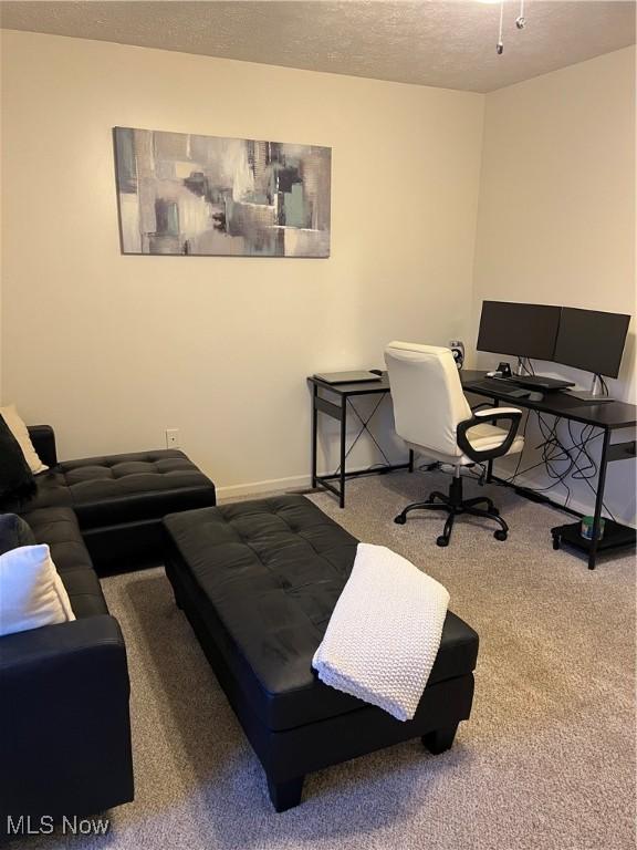 carpeted office with a textured ceiling and baseboards