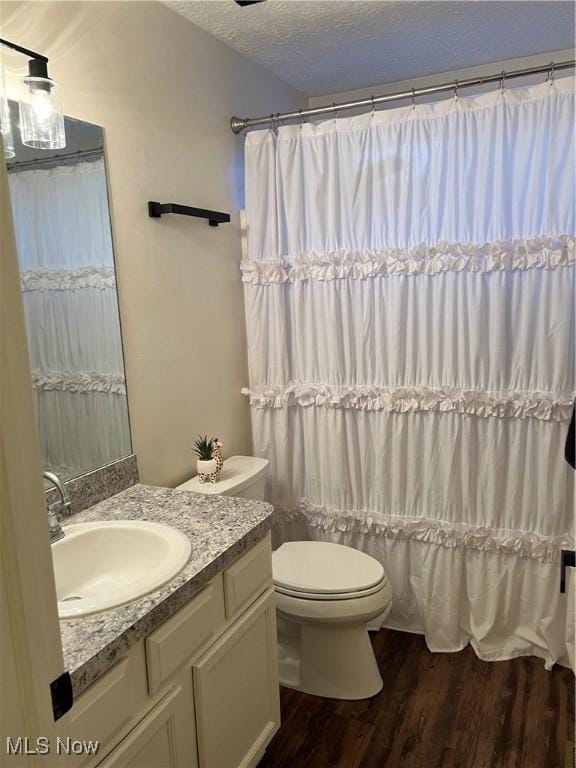 full bath featuring a shower with curtain, toilet, a textured ceiling, vanity, and wood finished floors