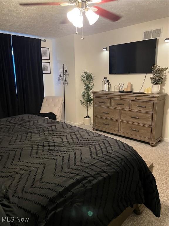 bedroom with visible vents, a textured ceiling, baseboards, and ceiling fan