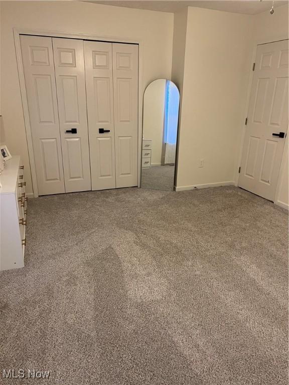 unfurnished bedroom featuring a closet, carpet flooring, and baseboards