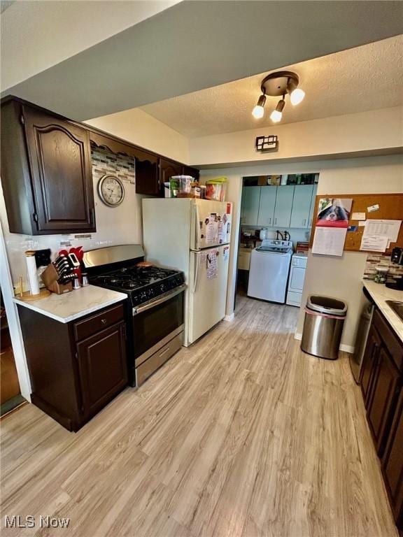 kitchen featuring separate washer and dryer, light wood-type flooring, light countertops, and gas stove