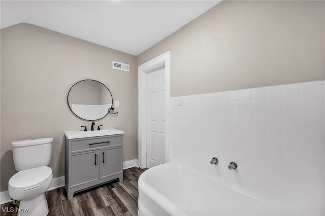 bathroom with vanity, visible vents, a washtub, toilet, and wood finished floors