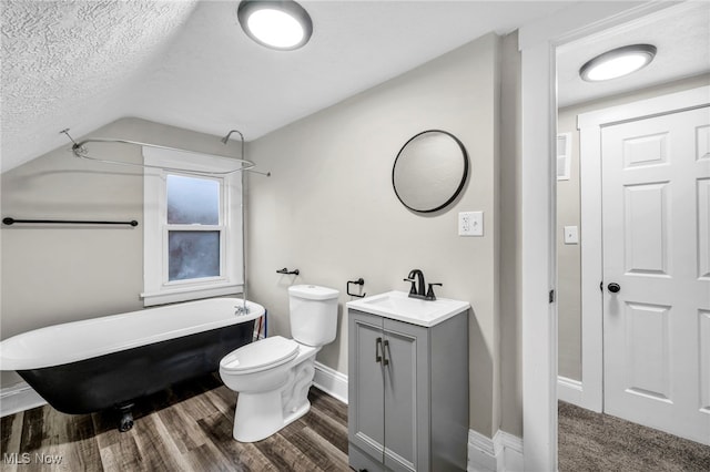 bathroom featuring a textured ceiling, a freestanding tub, vanity, toilet, and wood finished floors