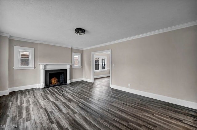 unfurnished living room featuring a lit fireplace, dark wood-style flooring, baseboards, and ornamental molding