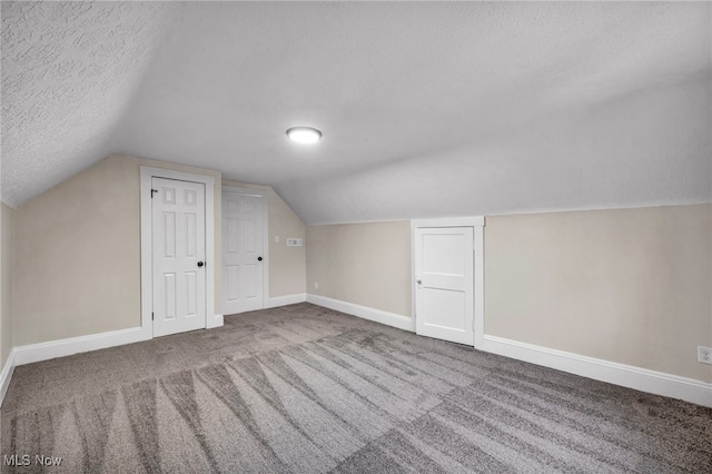 additional living space with vaulted ceiling, baseboards, a textured ceiling, and carpet floors