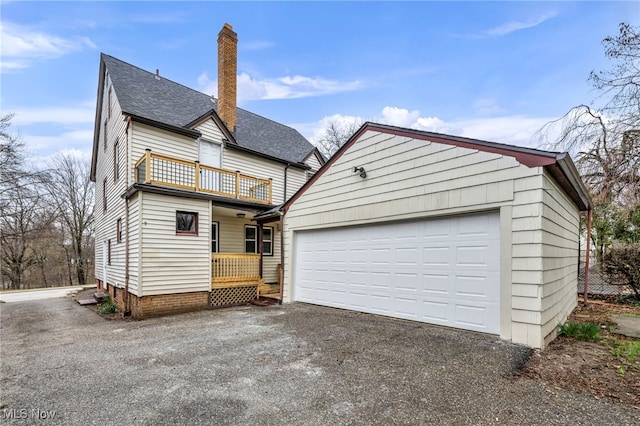 view of front of home featuring a chimney, a garage, aphalt driveway, and a balcony